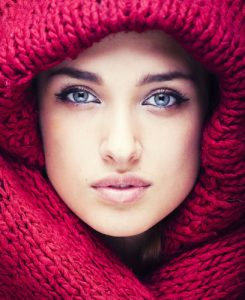 Close up of woman wrapped in red knitted scarf and hat