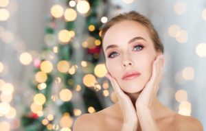 Woman touching her face in front of a christmas tree