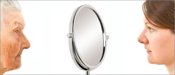 Old woman looking through a mirror at a young woman